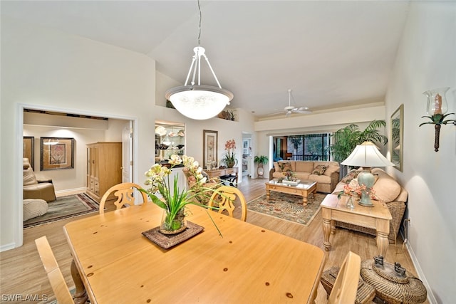 dining room with high vaulted ceiling, ceiling fan, and light wood-type flooring