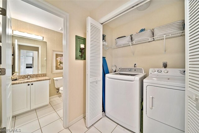 clothes washing area with light tile floors, washing machine and dryer, hookup for an electric dryer, and sink