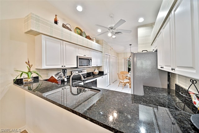 kitchen featuring ceiling fan, appliances with stainless steel finishes, dark stone countertops, white cabinets, and tasteful backsplash