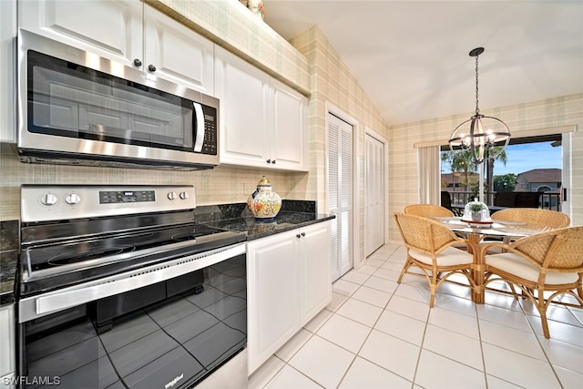 kitchen featuring white cabinets, a chandelier, stainless steel appliances, and lofted ceiling