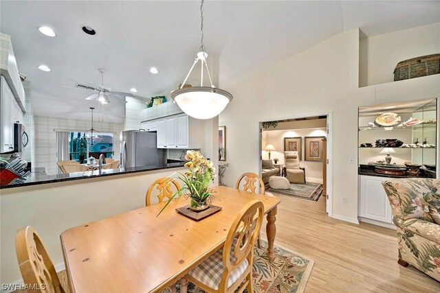 dining area with a fireplace, ceiling fan, and light hardwood / wood-style flooring