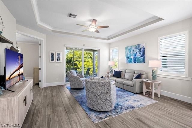 living room featuring hardwood / wood-style flooring, ceiling fan, and a tray ceiling