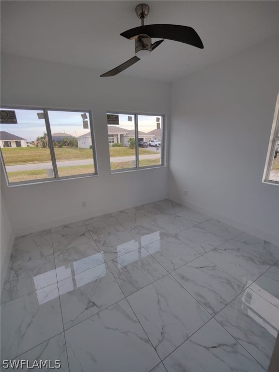 empty room featuring a healthy amount of sunlight, ceiling fan, and light tile floors