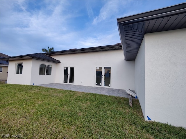 rear view of property featuring a patio, a yard, and french doors