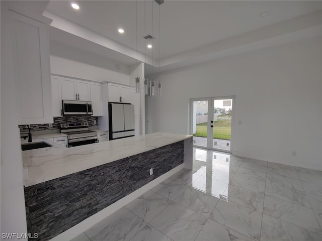 kitchen featuring pendant lighting, light tile flooring, a high ceiling, stainless steel appliances, and light stone counters