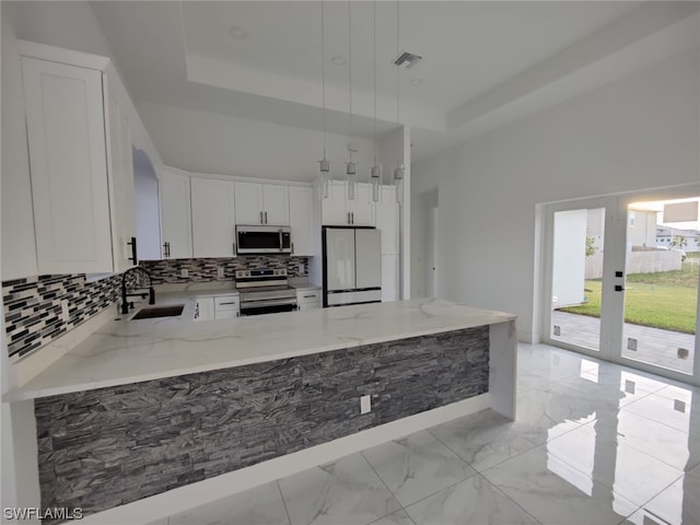 kitchen featuring decorative light fixtures, a tray ceiling, kitchen peninsula, stainless steel appliances, and sink