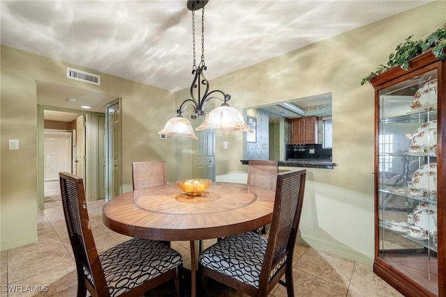 tiled dining room with a chandelier