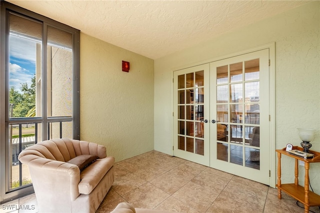 living area with french doors, a textured ceiling, and light tile patterned floors