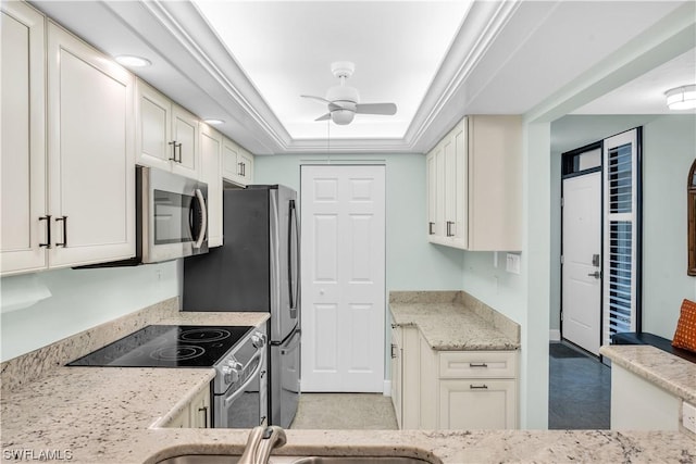 kitchen featuring a raised ceiling, white cabinetry, ceiling fan, and appliances with stainless steel finishes