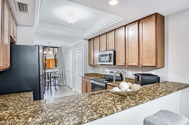 kitchen with stainless steel appliances, decorative light fixtures, a raised ceiling, dark stone countertops, and an inviting chandelier