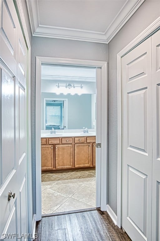 bathroom featuring ornamental molding, dual sinks, vanity with extensive cabinet space, and hardwood / wood-style flooring