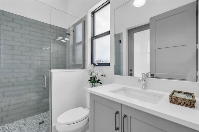 bathroom featuring toilet, a shower with shower door, and vanity