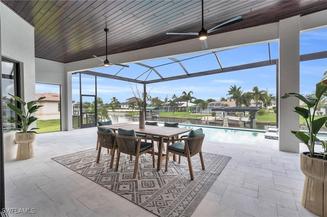 sunroom featuring a water view, ceiling fan, and wood ceiling