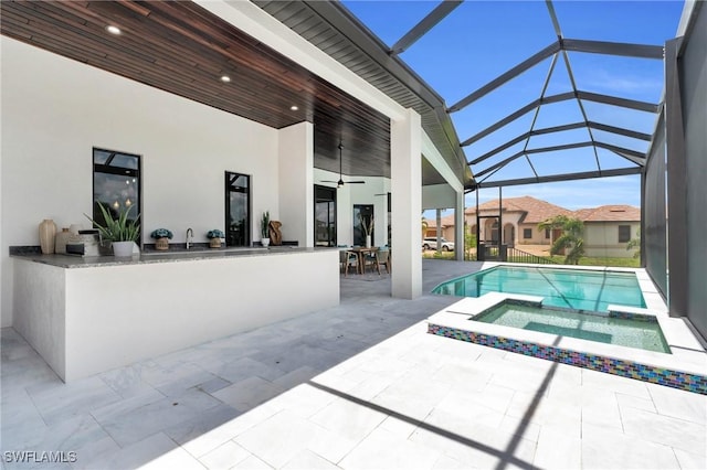 view of swimming pool with glass enclosure, an outdoor bar, an in ground hot tub, ceiling fan, and a patio area