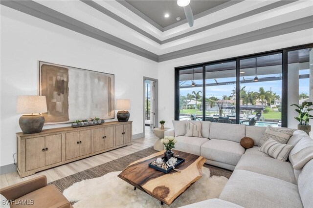 living room with a tray ceiling, ceiling fan, and light hardwood / wood-style floors