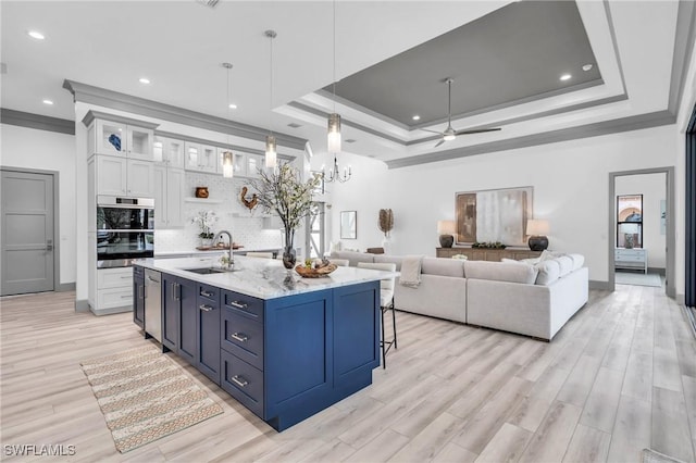 kitchen with decorative light fixtures, ceiling fan with notable chandelier, light hardwood / wood-style floors, white cabinetry, and sink