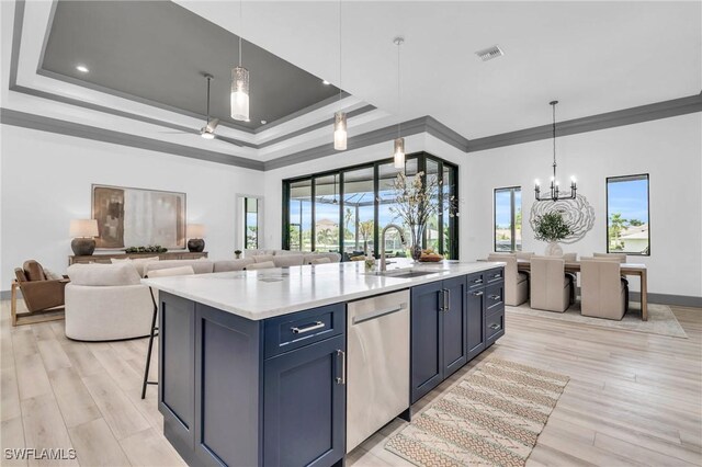 kitchen with an island with sink, dishwasher, blue cabinetry, and light hardwood / wood-style flooring