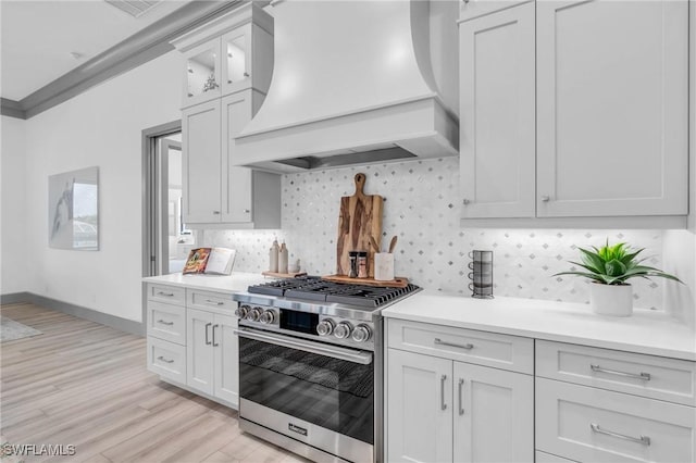 kitchen with light hardwood / wood-style floors, crown molding, custom exhaust hood, high end range, and white cabinets