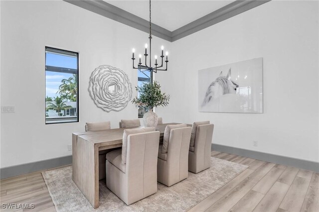 dining space featuring ornamental molding, an inviting chandelier, and light hardwood / wood-style flooring