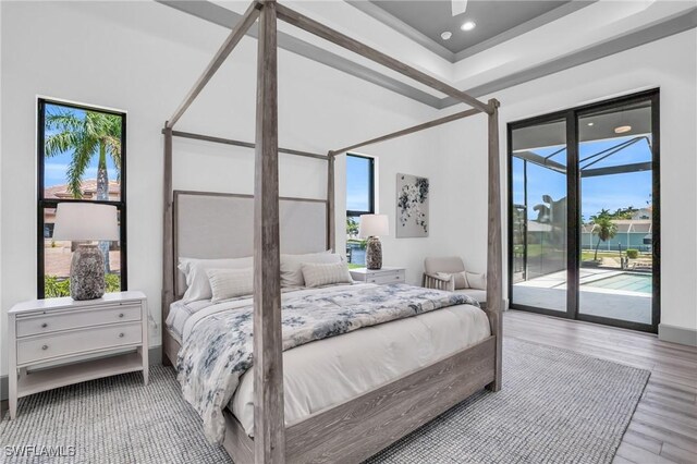 bedroom with multiple windows, access to outside, and light hardwood / wood-style floors