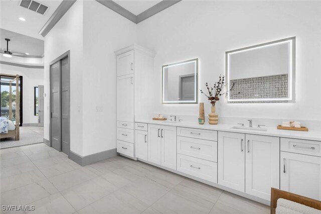 bathroom with a high ceiling, ceiling fan, ornamental molding, and vanity