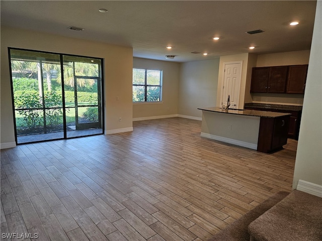 kitchen featuring hardwood / wood-style flooring, a center island with sink, dark brown cabinetry, and sink