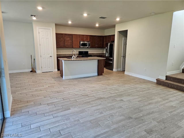 kitchen featuring black refrigerator with ice dispenser, range, a kitchen island with sink, light hardwood / wood-style flooring, and dark brown cabinetry