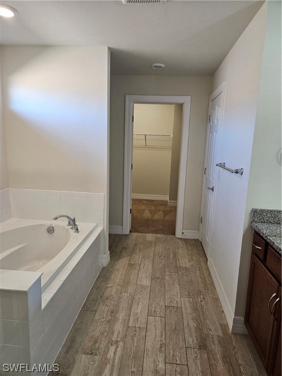 bathroom featuring vanity, a relaxing tiled bath, and hardwood / wood-style flooring