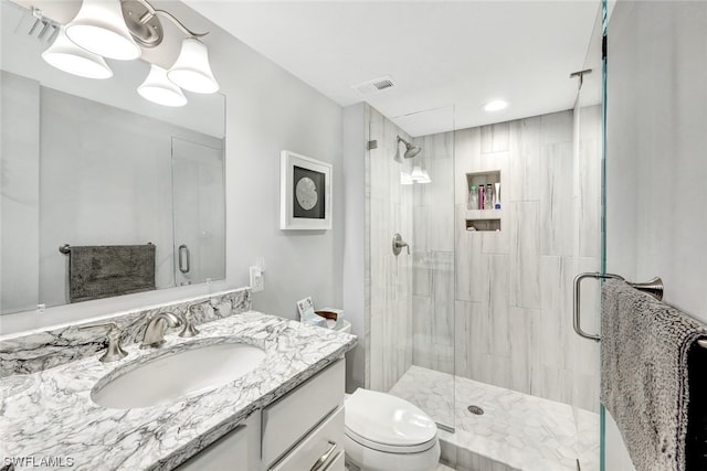 bathroom featuring toilet, large vanity, and an enclosed shower