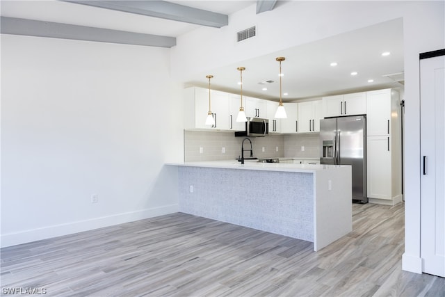 kitchen with stainless steel appliances, beam ceiling, kitchen peninsula, white cabinets, and light wood-type flooring