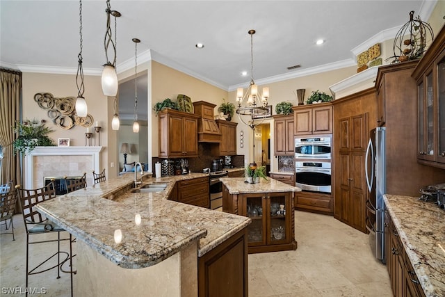 kitchen with decorative light fixtures, backsplash, a fireplace, a kitchen breakfast bar, and sink