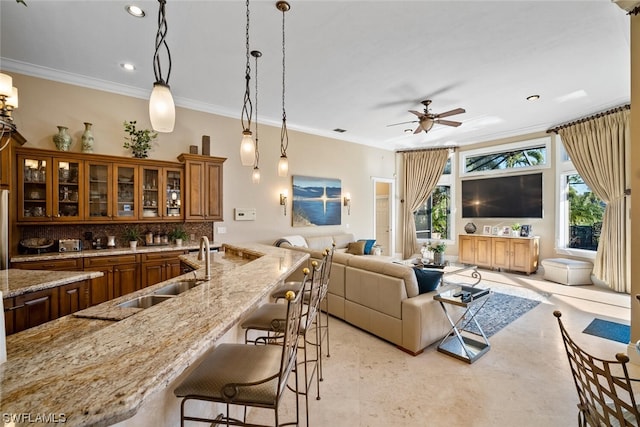 kitchen with decorative light fixtures, light stone countertops, ceiling fan, and a breakfast bar area