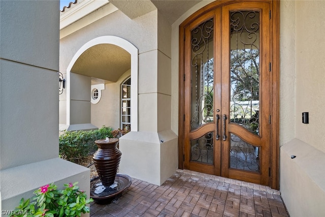 property entrance with covered porch and french doors