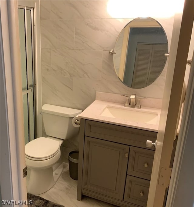 bathroom with vanity, tile flooring, toilet, and tile walls