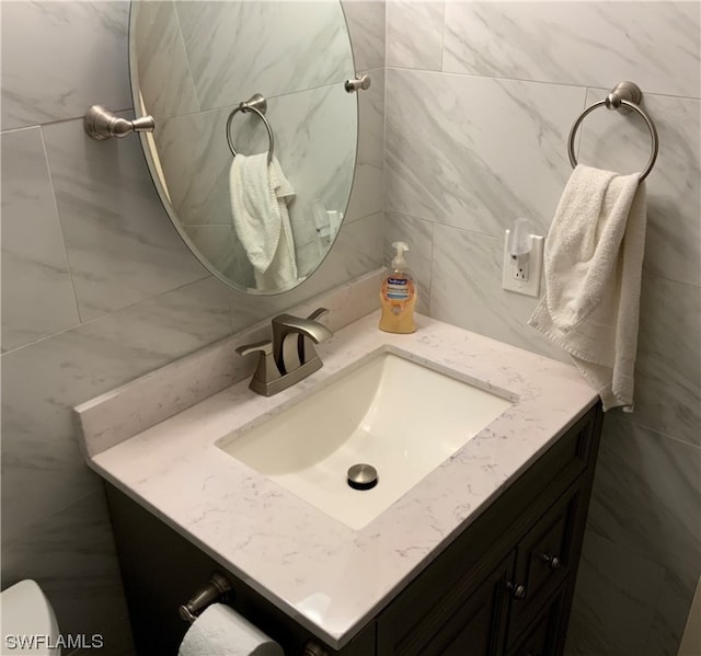 bathroom with oversized vanity, toilet, and tile walls