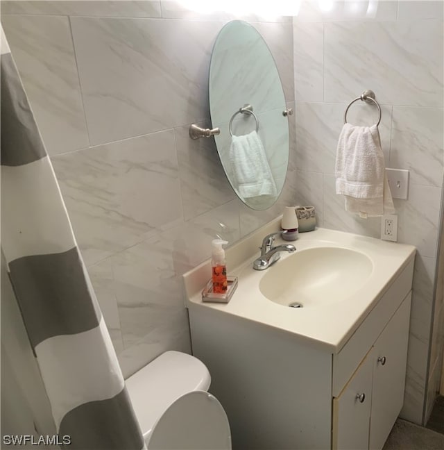 bathroom featuring tile walls, large vanity, and toilet