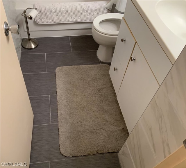 bathroom featuring toilet, vanity, and tile flooring