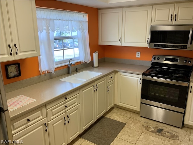 kitchen featuring light tile floors, appliances with stainless steel finishes, white cabinetry, and sink