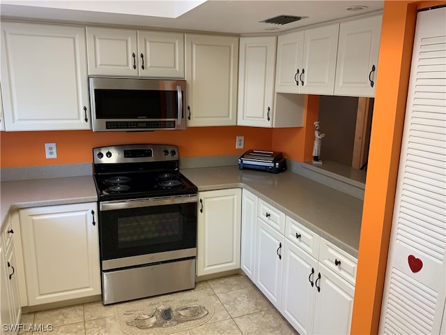 kitchen with white cabinets, appliances with stainless steel finishes, and light tile floors