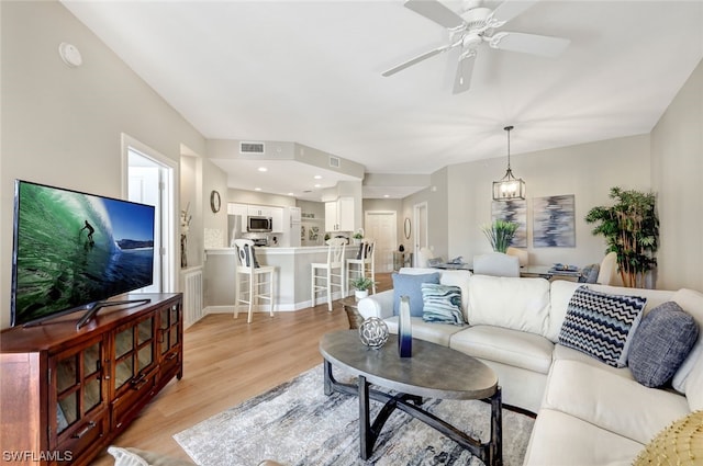 living room with ceiling fan and light hardwood / wood-style flooring