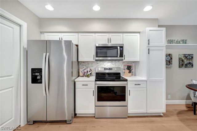 kitchen with light wood-type flooring, white cabinets, appliances with stainless steel finishes, and tasteful backsplash