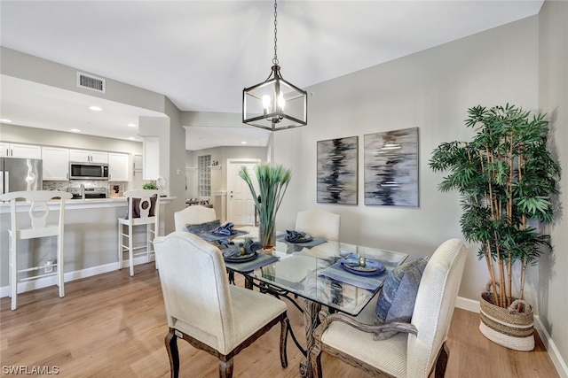 dining room with an inviting chandelier and light hardwood / wood-style flooring