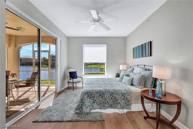 bedroom featuring a water view, ceiling fan, hardwood / wood-style flooring, and access to outside