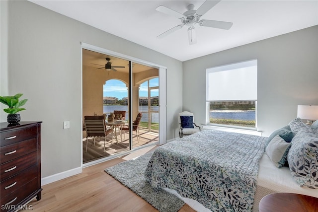 bedroom featuring light hardwood / wood-style flooring, ceiling fan, a water view, and access to outside