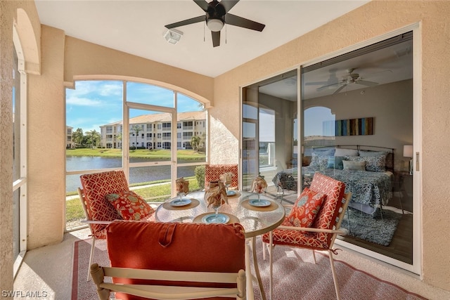 sunroom / solarium with ceiling fan and a water view