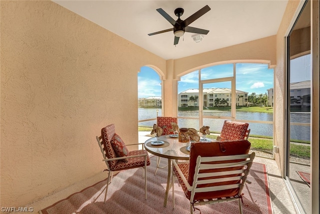 sunroom / solarium featuring a water view and ceiling fan