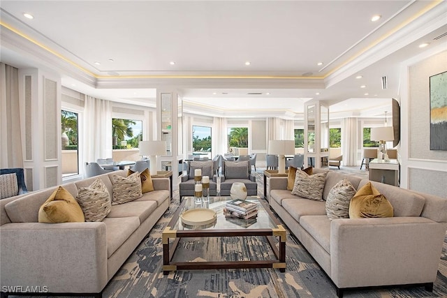 living room featuring a raised ceiling, crown molding, and plenty of natural light