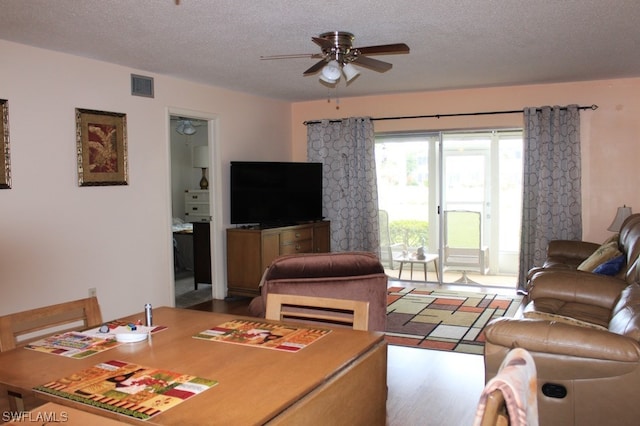 living room featuring ceiling fan and a textured ceiling