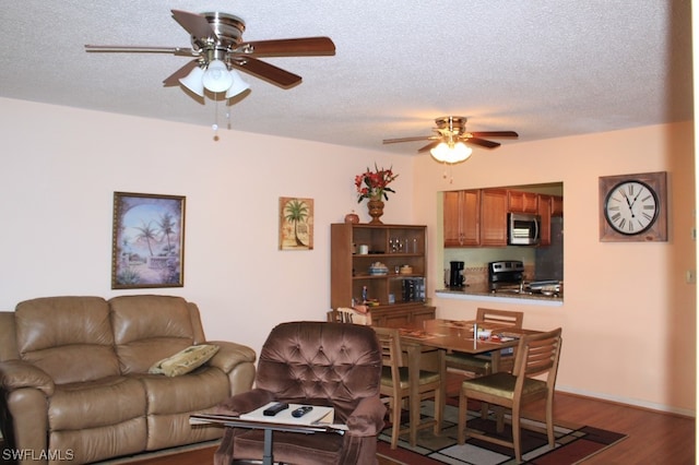 living room with a textured ceiling, ceiling fan, and dark wood-type flooring