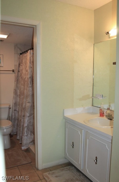 bathroom featuring tile flooring, large vanity, and toilet